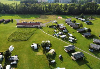 Luchtfoto van safaritenten, caravans en gebouwen op Camping de Regenboog in Tsjechië, omringd door grasvelden.