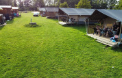 Safari-Zelte und Hütten auf Camping de Regenboog in Tschechien, mit Menschen, die auf der Veranda entspannen.