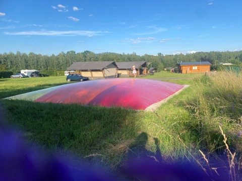 Eine aufblasbare Hüpfburg vor Safarizelten auf Camping de Regenboog in Tschechien bei klarem Himmel.