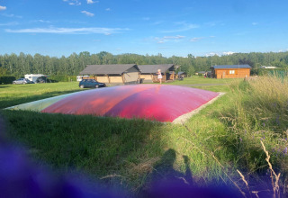 Eine aufblasbare Hüpfburg vor Safarizelten auf Camping de Regenboog in Tschechien bei klarem Himmel.