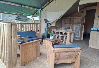 Tenda safari con servizi igienici al campeggio de Zeven Heuveltjes, con arredi in legno e veranda coperta.