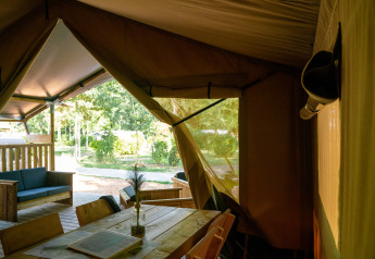 Indvendig udsigt fra en safaritelt med træmøbler og udsigt til den grønne natur på Camping de Zeven Heuveltjes.