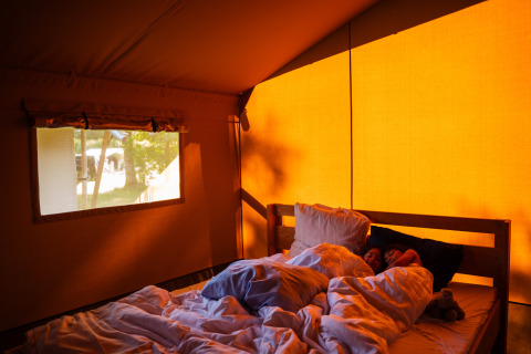 Zwei Personen schlafen in einem Bett im beleuchteten Safarizelt auf dem Camping de Chênefleur in Belgien.