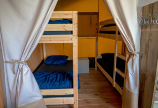 Foto von einem Schlafzimmer im Safarizelt mit zwei Etagenbetten, blauer Bettwäsche und Holzfußboden.