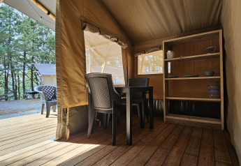 Innenansicht eines Safarizeltes auf dem Campingplatz Luna del Monte in Italien, mit Stühlen, Tisch und Regal.