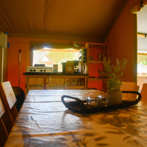 Intérieur d'une tente safari avec table à manger et cuisine au Camping du Rivage au Luxembourg.
