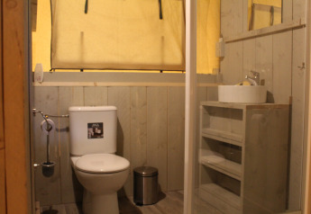 Bagno in tenda safari con wc, lavandino e specchio al Family park Goolderheide in Belgio.