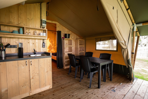 Innenraum eines Safarizelts mit Küche, Esstisch und Holzdekor im Family Park Goolderheide in Belgien.