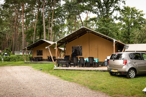 Tente safari au Family Park Goolderheide en Belgique, avec terrasse extérieure et voiture garée devant.