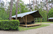 Safari-Zelt mit Terrasse und Stühlen im grünen Wald des Family Parks Goolderheide, Belgien.