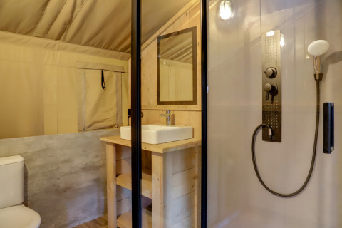 Interior of safari tent bathroom at Family park Goolderheide, Belgium, with shower, sink, and toilet visible.