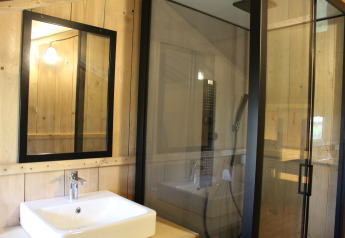 Badezimmer im Safari-Zelt + Sanitär im Family Park Goolderheide, Belgien, mit Spiegel und Duschkabine.