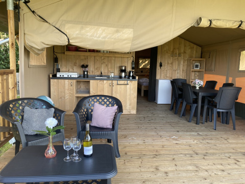 Safaritent met houten terras, zitje en keuken op Camping Dal van de Mosbeek in Nederland.