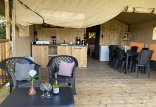 Safaritent met houten terras, zitje en keuken op Camping Dal van de Mosbeek in Nederland.