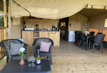 Safari-Zelt mit Holzterrasse, gemütlichen Sitzgelegenheiten und Küche auf dem Campingplatz Dal van de Mosbeek.