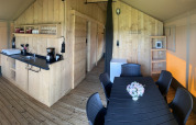 Innenansicht eines Safari-Zeltes mit Küche, Esstisch und modernen Annehmlichkeiten auf Campingplatz Dal van de Mosbeek.