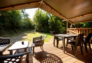 View from Safari tent with sanitary at Campsite Fargogne, outdoor deck with seating and dining tables.