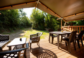Vue depuis une tente safari avec sanitaire au camping Fargogne, terrasse extérieure avec mobilier.