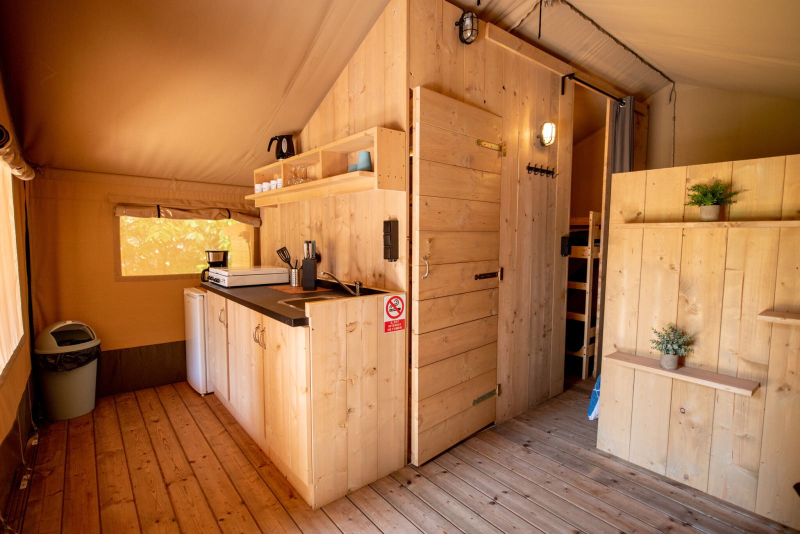 Interieur van een Safari-tent met houten keuken en badkamer op Camping Fargogne, Frankrijk, knusse sfeer.