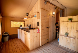 Interno di tenda Safari con cucina e bagno in legno al Campeggio Fargogne, Francia, atmosfera accogliente.