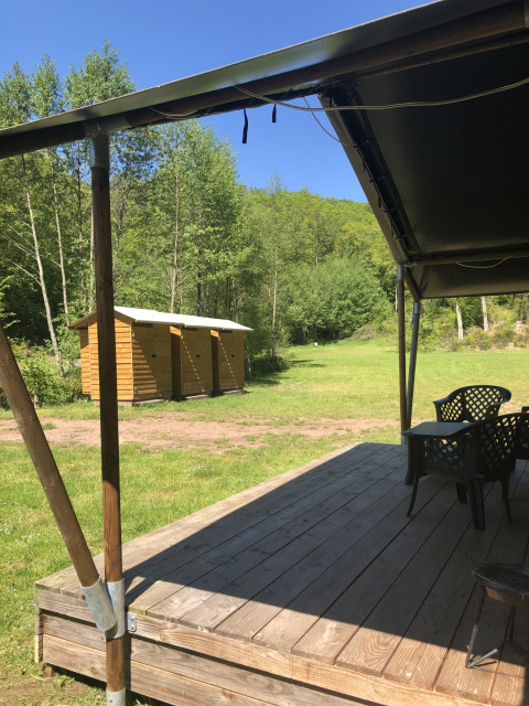 Vista dalla veranda in legno verso i bagni e la natura presso la Safari tent al campeggio Bockenauer Schweiz.