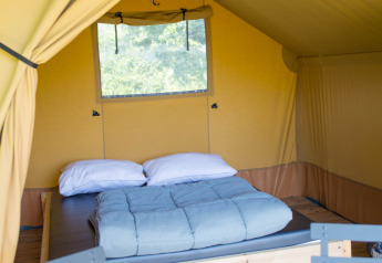 Interior of the Duo Lodge safari tent at Campsite de Boomgaard in Belgium, showing a cozy bed and decor.