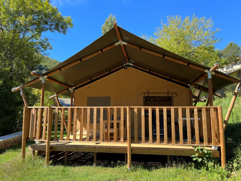 Safari tent at Campsite l’Ardéchois in France, viewed from the front, with wooden deck and greenery.