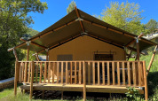 Tenda safari al Campeggio l’Ardéchois in Francia, vista frontale con veranda in legno e natura attorno.