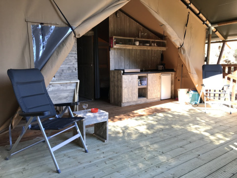 Interno di una tenda safari con sedie e angolo cottura al Campeggio Les Lauriers Roses in Francia.