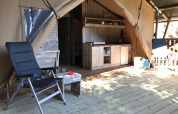 Innenbereich eines Safarizelts mit Stühlen und Küchenzeile auf dem Campingplatz Les Lauriers Roses in Frankreich.