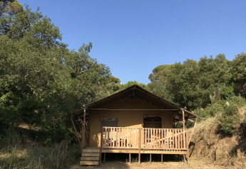 Safari-telt ved Campingplads Les Lauriers Roses i Frankrig, placeret blandt træer under en blå himmel.