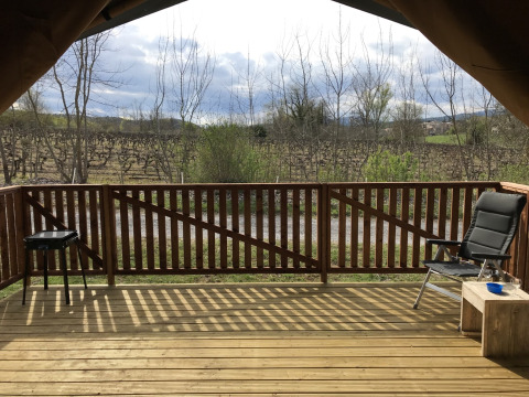 Vista dal patio di una tenda safari al Campeggio Saint Amand in Francia, con sedia e barbecue.