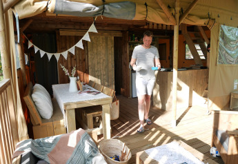 Mann auf der Veranda des Safarizeltes Lodge Tent auf dem Campingplatz Paradiso in Italien, sonnig.