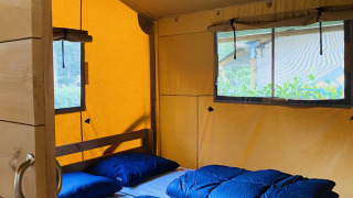 Interno di una tenda safari per sei persone con biancheria da letto blu al campeggio De Rammelbeek nei Paesi Bassi.