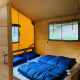 Interior de una tienda safari para seis personas con ropa de cama azul en el camping De Rammelbeek, Países Bajos.