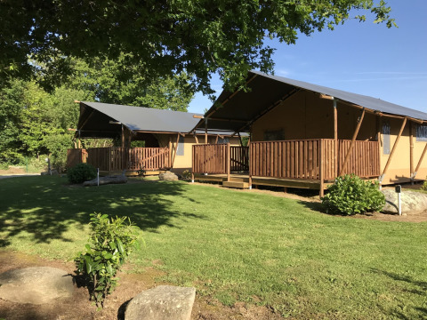 Safari tents with wooden decks at Campsite de Kerleyou in France, set in a green, tree-filled landscape.