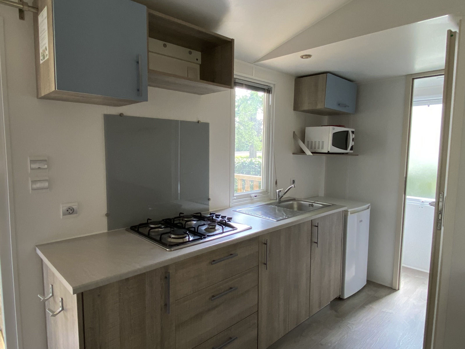 Compacte keuken in een stacaravan op Camping Le Céou in Frankrijk met gasfornuis, spoelbak en magnetron.