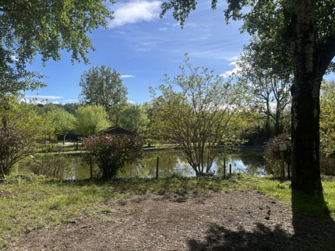 Mooi zicht op een rustige vijver omgeven door bomen in vakantiedomein Les Rives de Courtes, Occitanie, Frankrijk.
