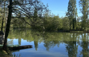 Vista de un lago tranquilo rodeado de árboles y césped en Les Rives de Courtes, Occitanie, Francia.