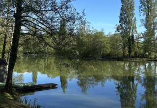 Photo d’un lac calme entouré d’arbres au parc de vacances Les Rives de Courtes en Occitanie, France.