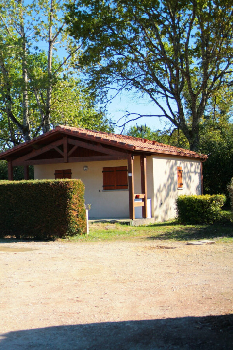 Vakantiehuis bij Les Rives de Courtes vakantiepark in Occitanië, Frankrijk, omgeven door bomen en zon.