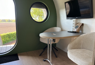 Innenansicht eines Anthropod Tiny Houses im Ferienpark 't Rheezerwold, Niederlande, mit Tisch und Stühlen.