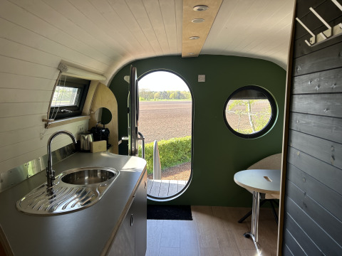 Intérieur de la tiny house Anthropod au parc de vacances 't Rheezerwold, avec cuisine et vue sur champ, Pays-Bas.