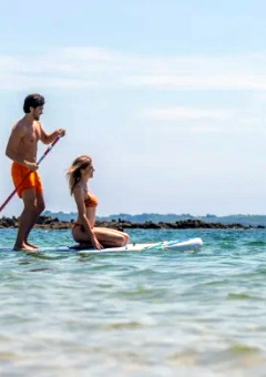 Twee personen paddleboarden op het water nabij Marina di Castagneto Carducci, Toscane, Italië.
