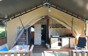 Innenraum eines Safarizelts auf dem Campingplatz de Kerleyou in Frankreich mit Ess- und Kochbereich.