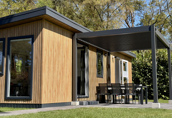 Tiny house moderne Forest Lodge, bardage bois, terrasse couverte et coin repas extérieur en pleine nature.