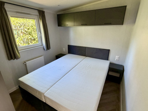 Camera da letto con due letti singoli, finestra con tende e armadietti al Forest Lodge, Krieghuusbelten.