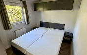 Camera da letto con due letti singoli, finestra con tende e armadietti al Forest Lodge, Krieghuusbelten.