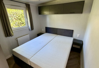 Camera da letto con due letti singoli, finestra con tende e armadietti al Forest Lodge, Krieghuusbelten.