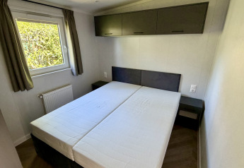 Slaapkamer met twee enkele bedden, raam met gordijnen en kasten in Forest Lodge, Krieghuusbelten.